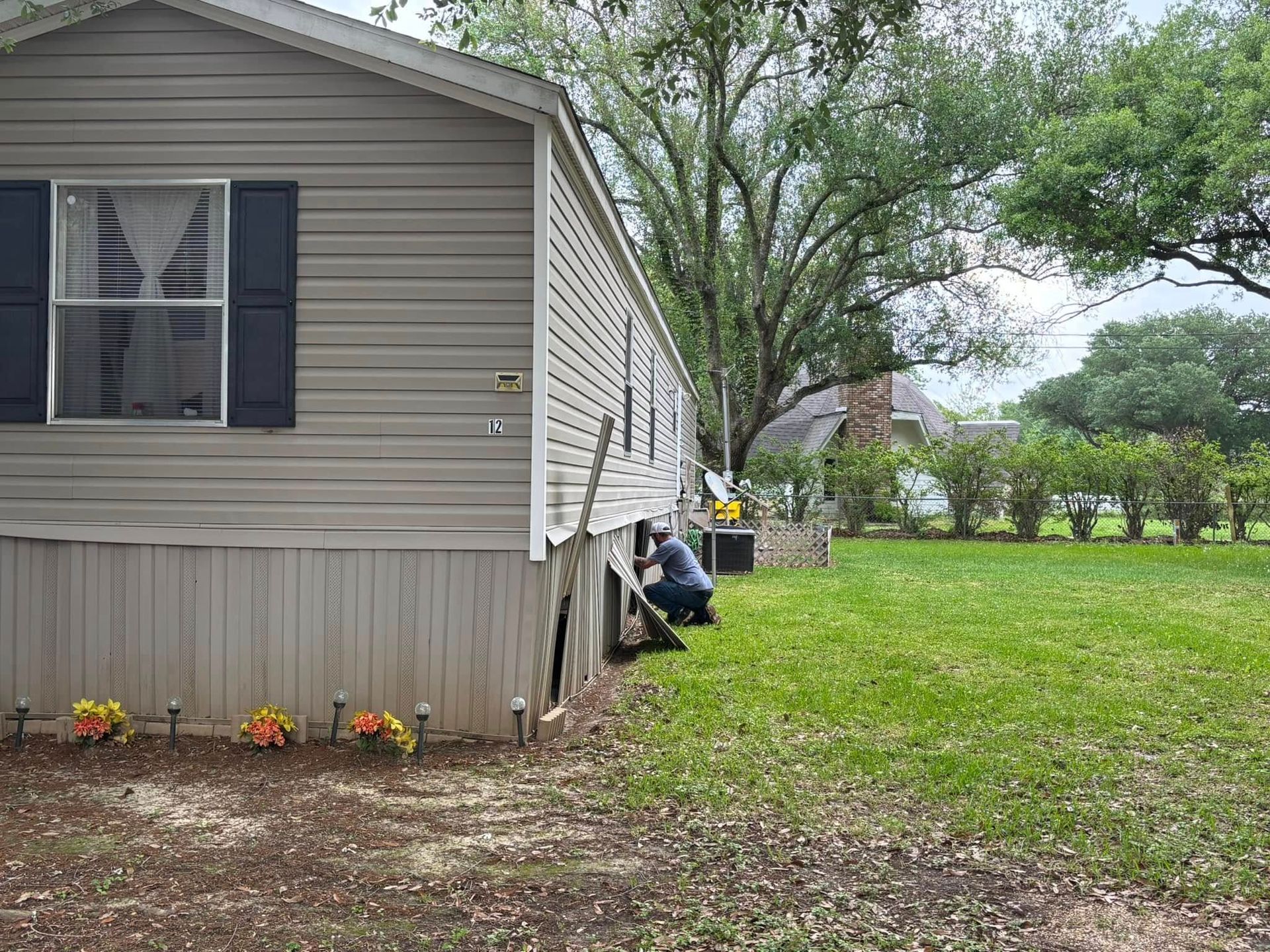 A man is kneeling in front of a mobile home.