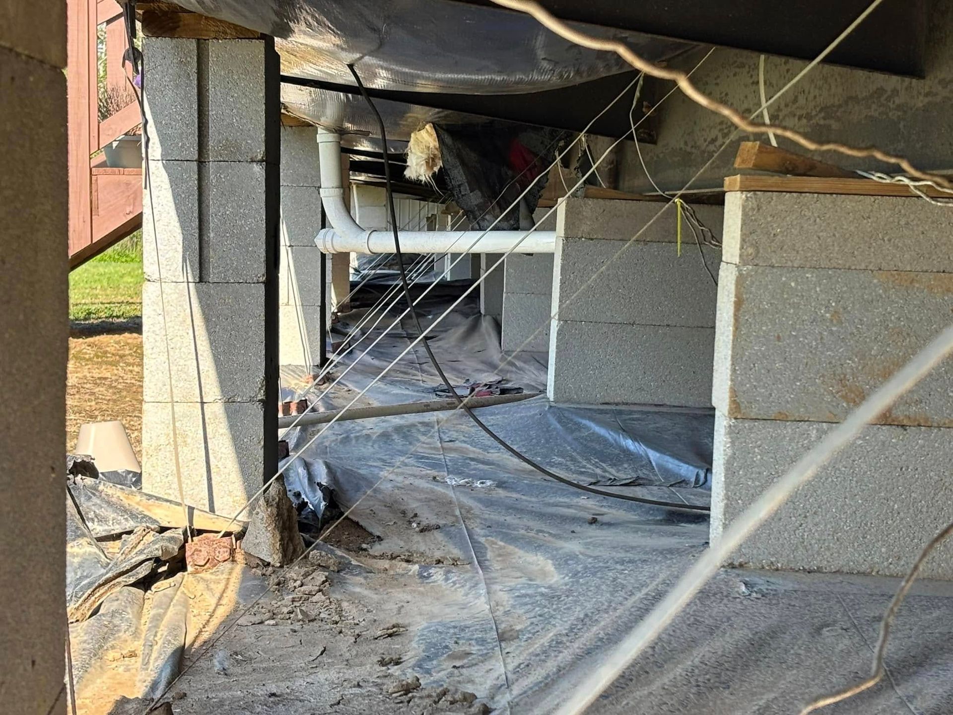 A broken foundation of a house with a lot of wires coming out of it.