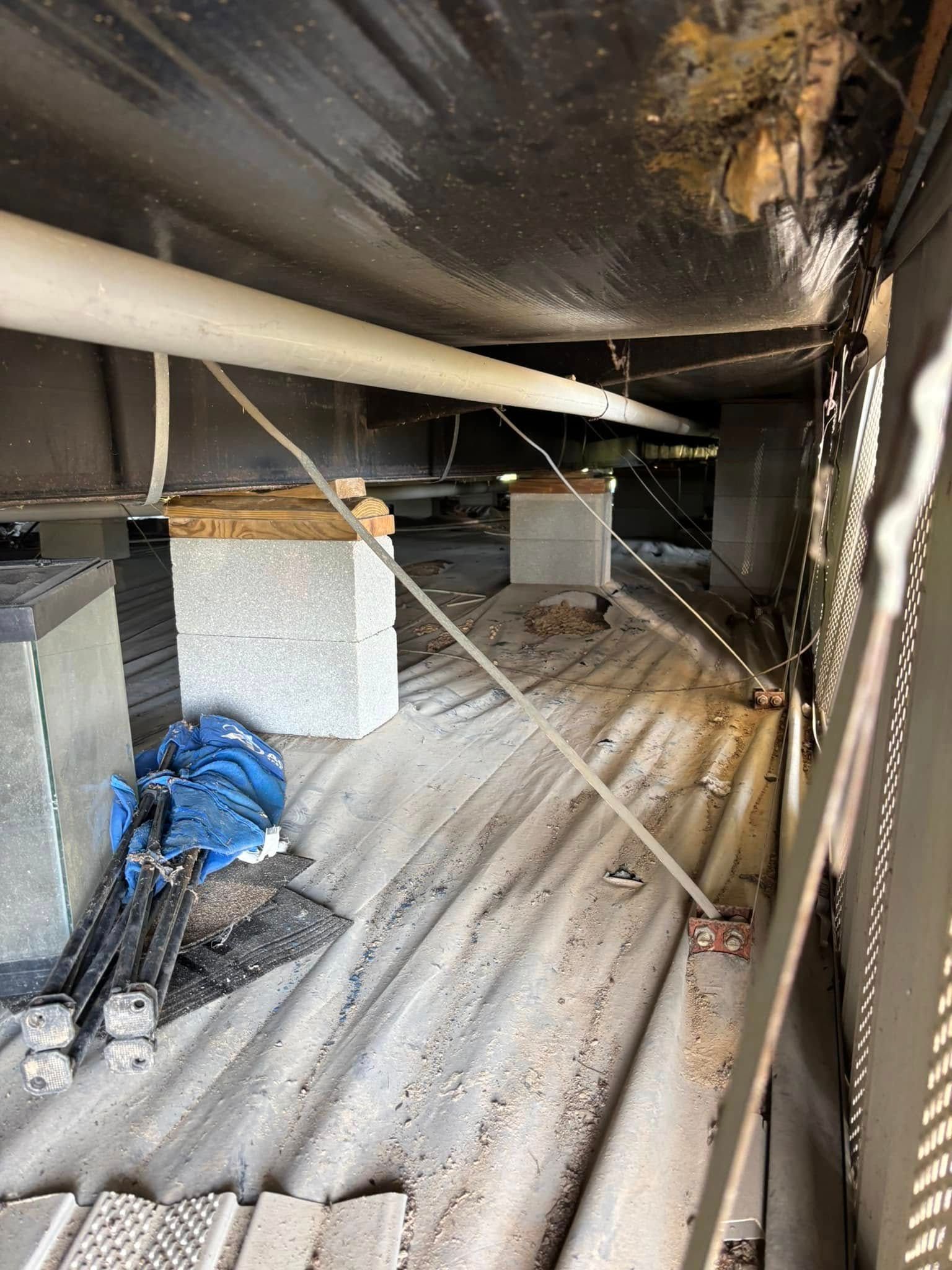 A room with a lot of pipes and a blue tarp on the floor.