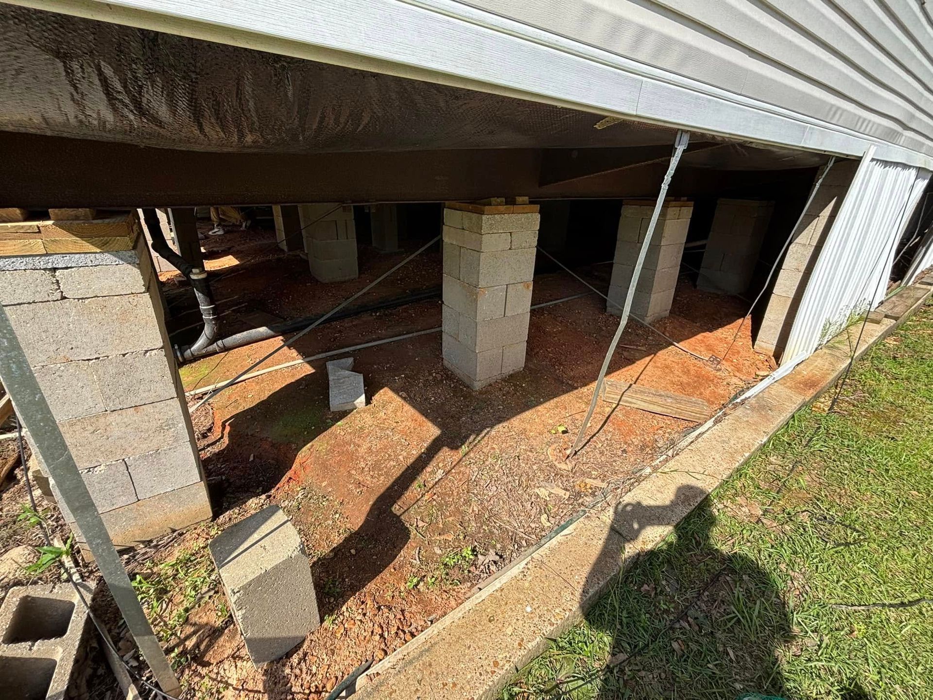 A shadow of a person is cast on the ground under a house.