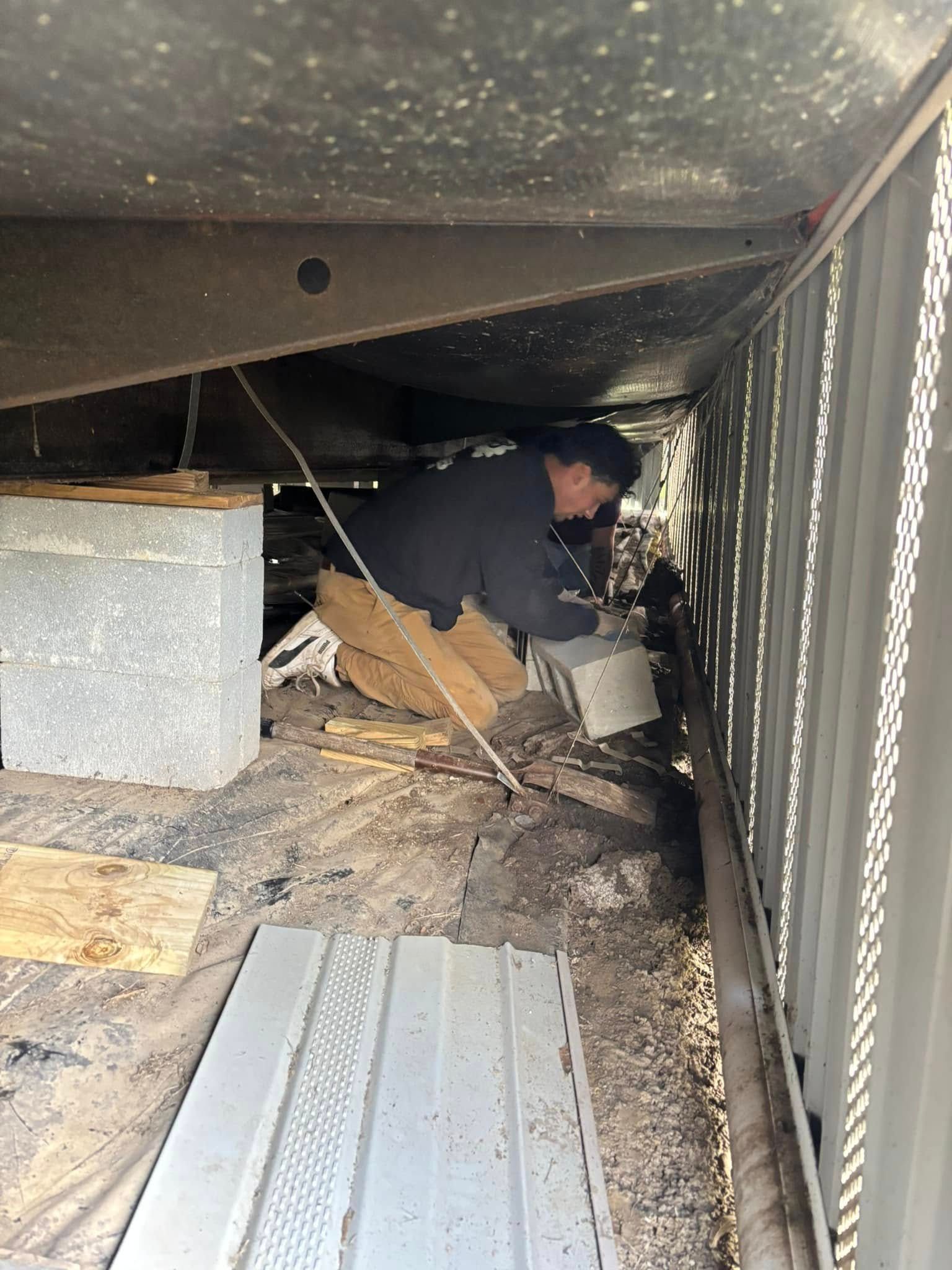 A man is working under a bridge with a bucket.
