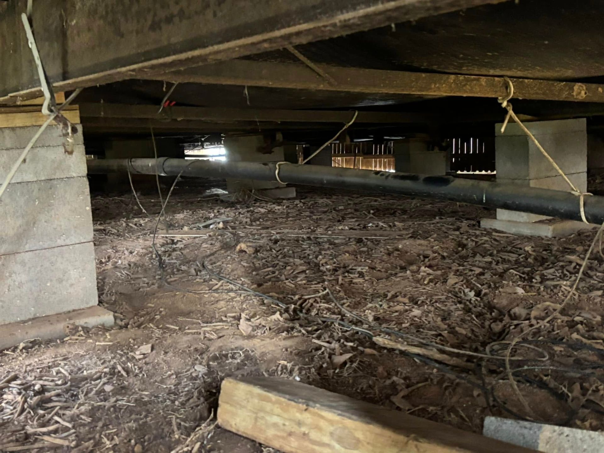 The underside of a building with a lot of dirt and wood.