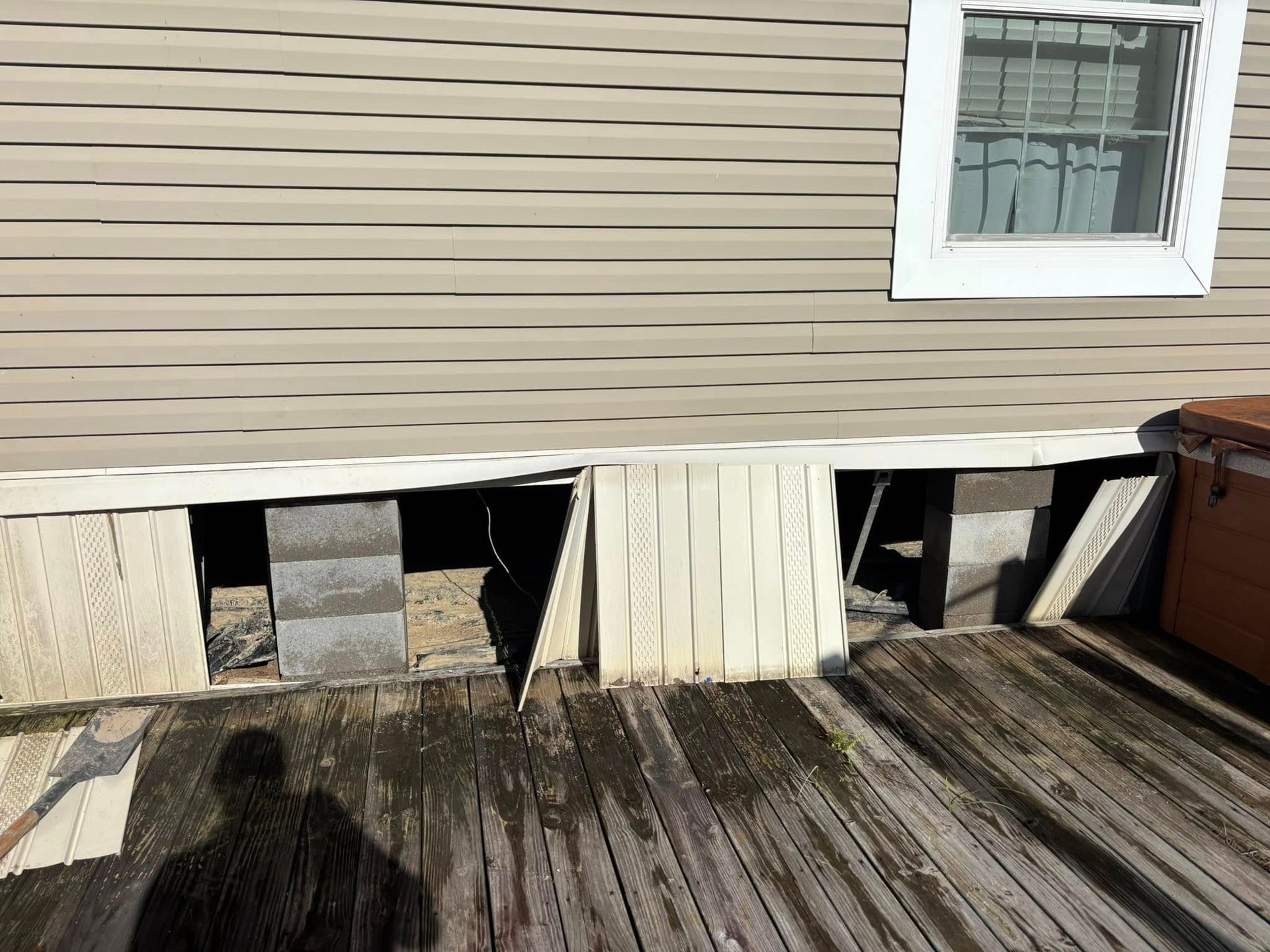 A shadow of a person is cast on a wooden deck in front of a house.