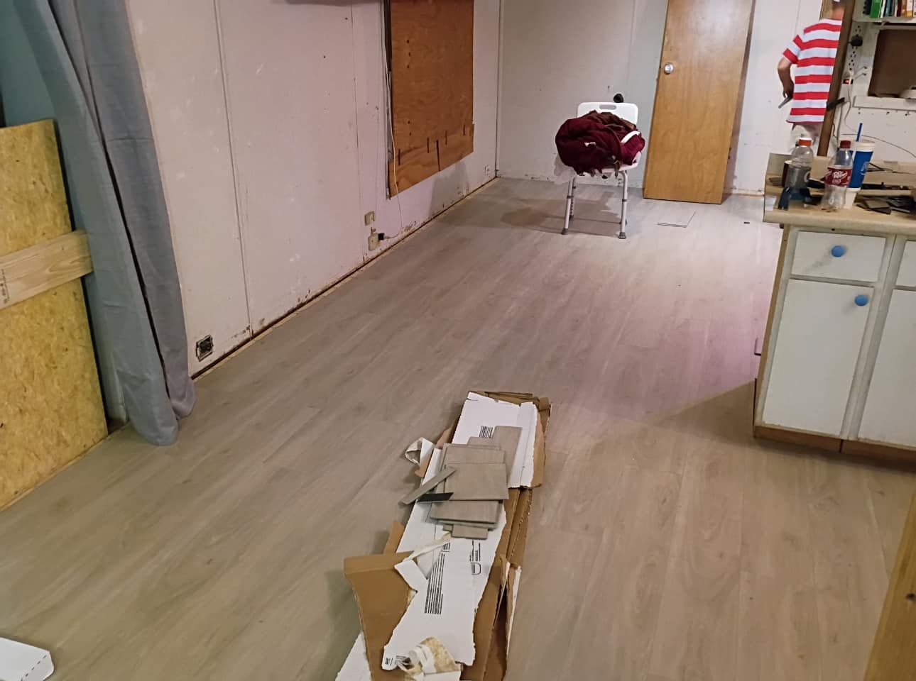Room with light-colored flooring; a person stands near a cabinet on the right.