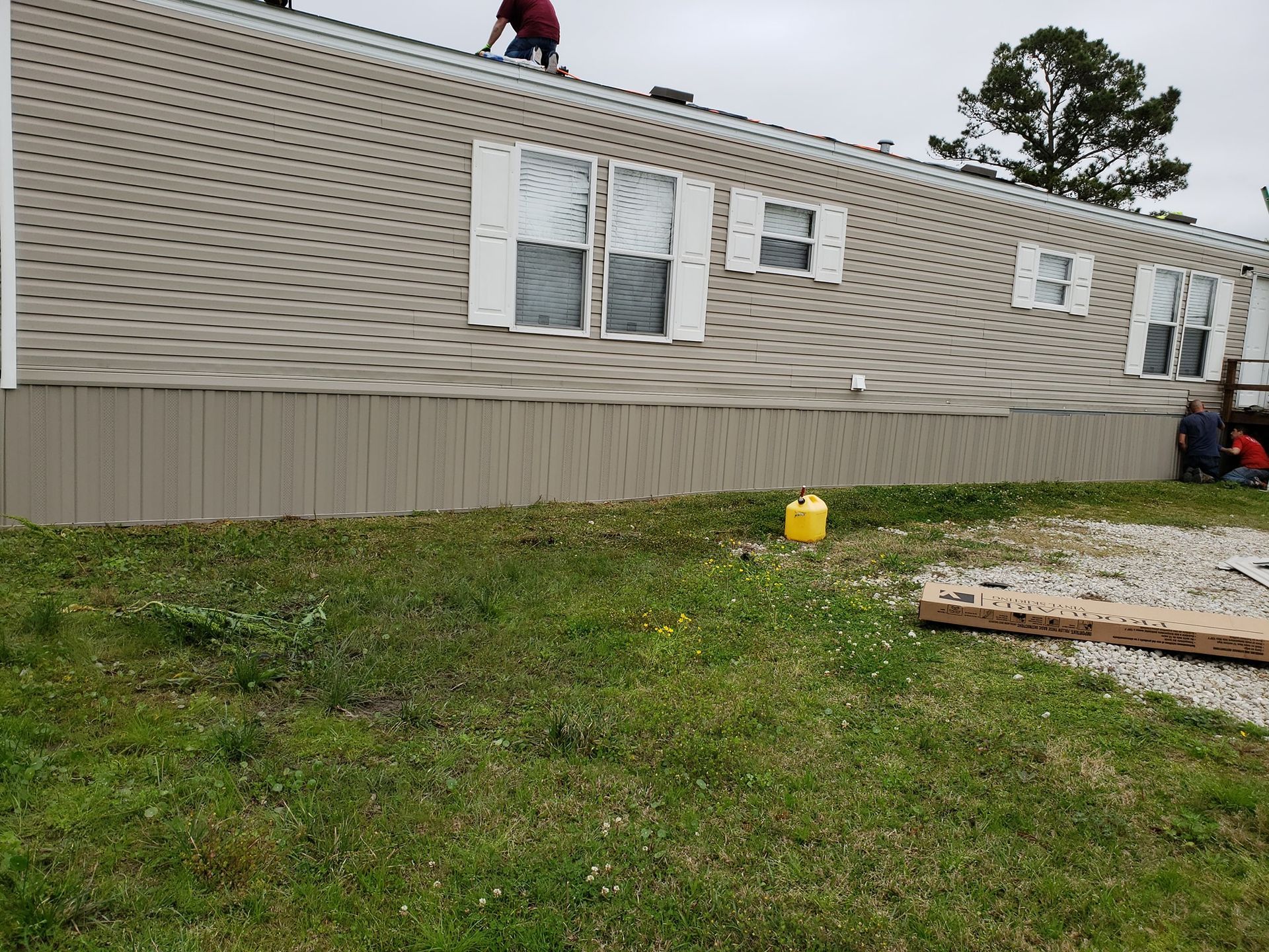 A man is standing on the roof of a mobile home.