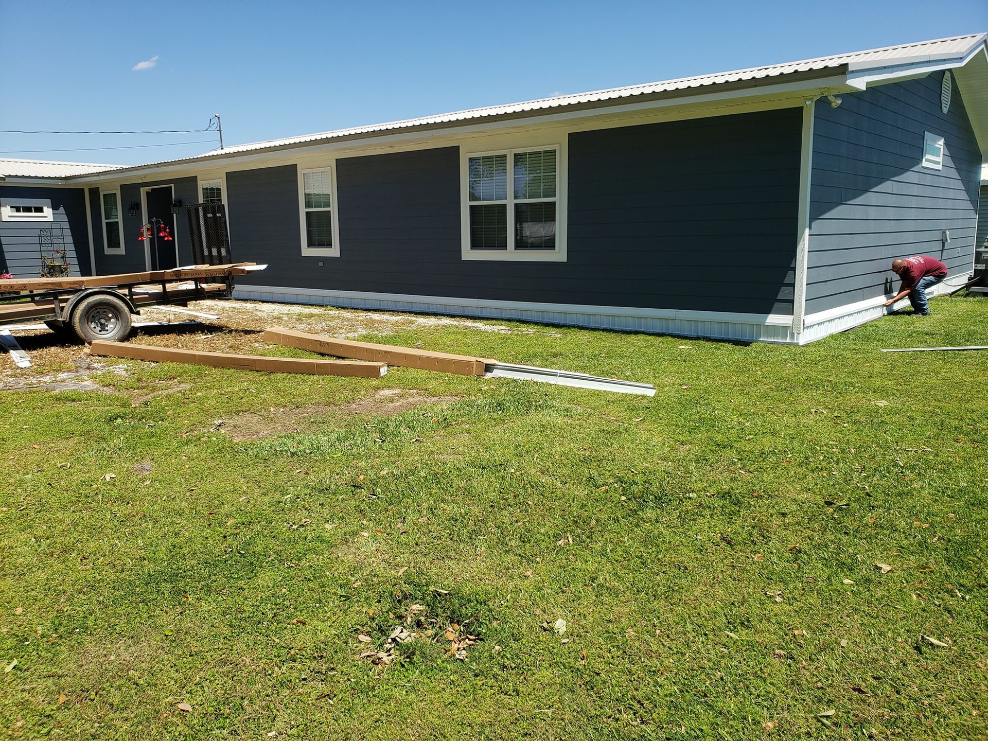 A mobile home is being built in a grassy yard.