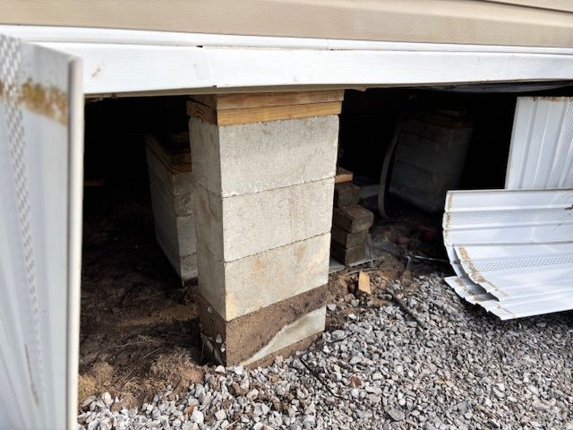 Concrete block support column under a structure, resting on gravel.