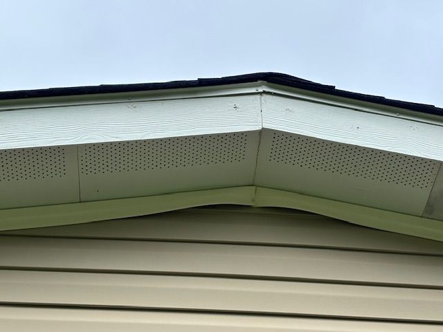 Beige siding with sagging, light green soffit and roofline.