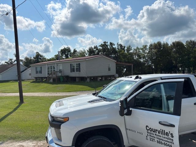 White pickup truck in front of a light-colored house, under a cloudy blue sky.