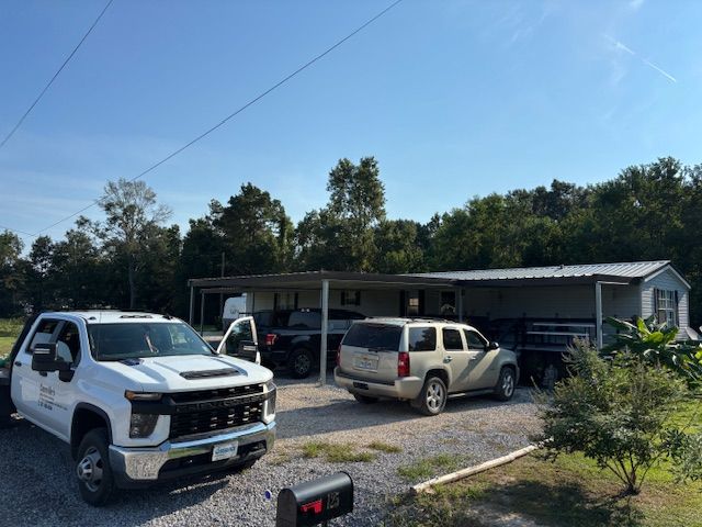 White truck, SUV, and trailer parked in front of a mobile home on a sunny day.
