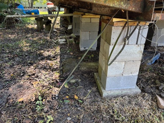Mobile home supported by stacked cinder blocks on uneven ground.