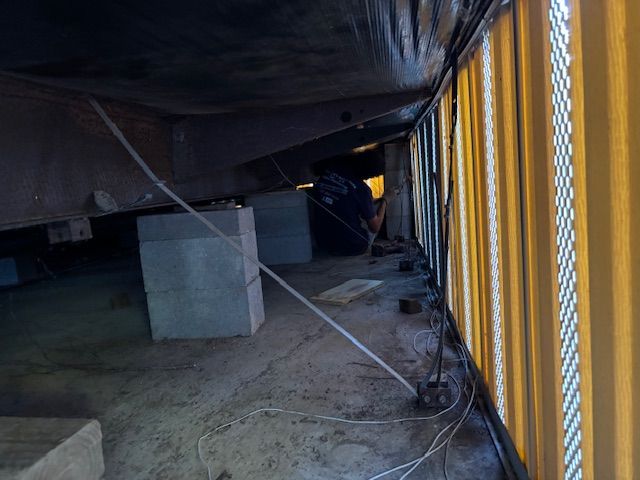 Inside a shipping container, concrete blocks support a structure. A person works in the shadows.