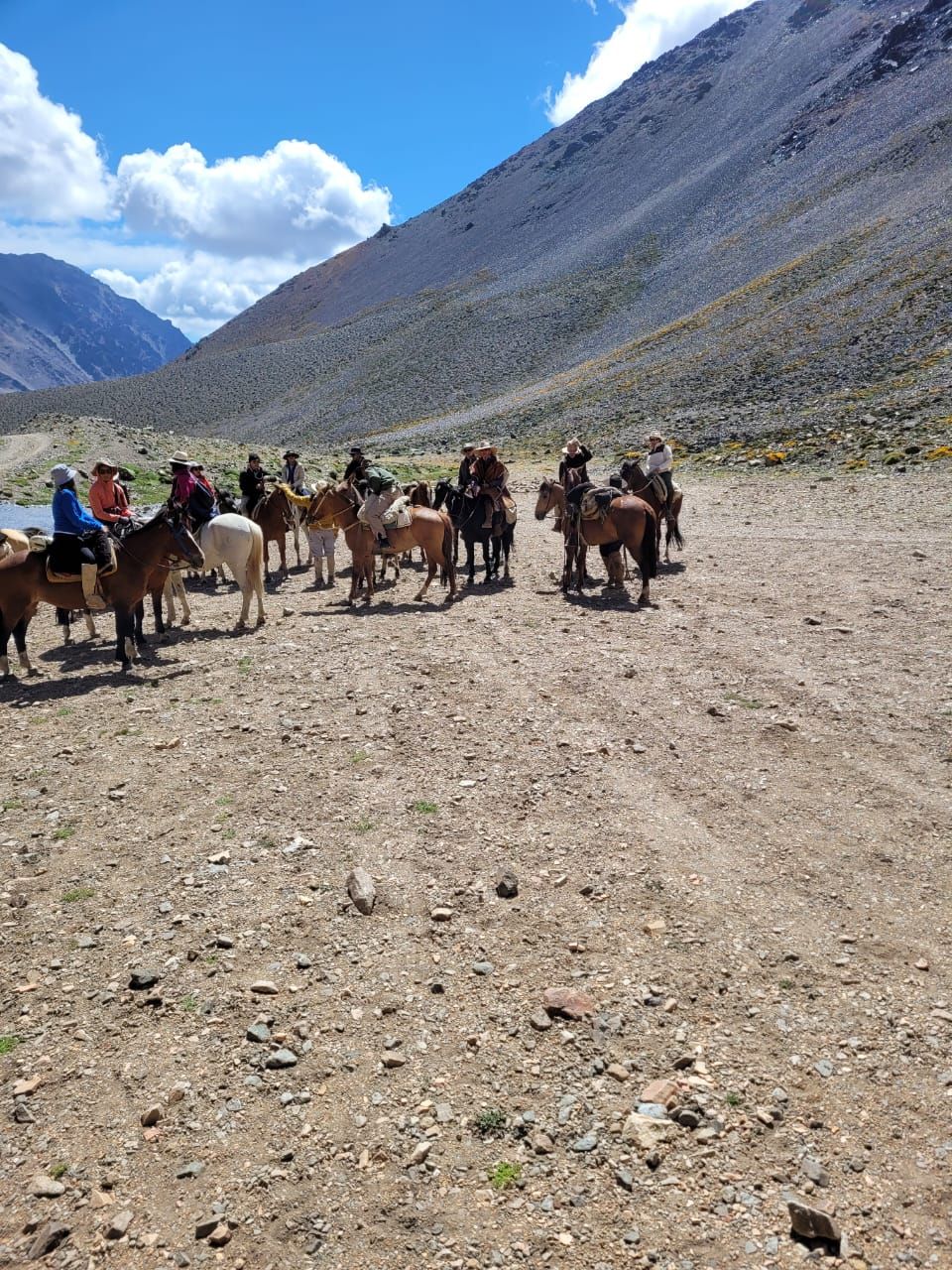 Grupo de jinetes a caballo en un paisaje rocoso y montañoso.