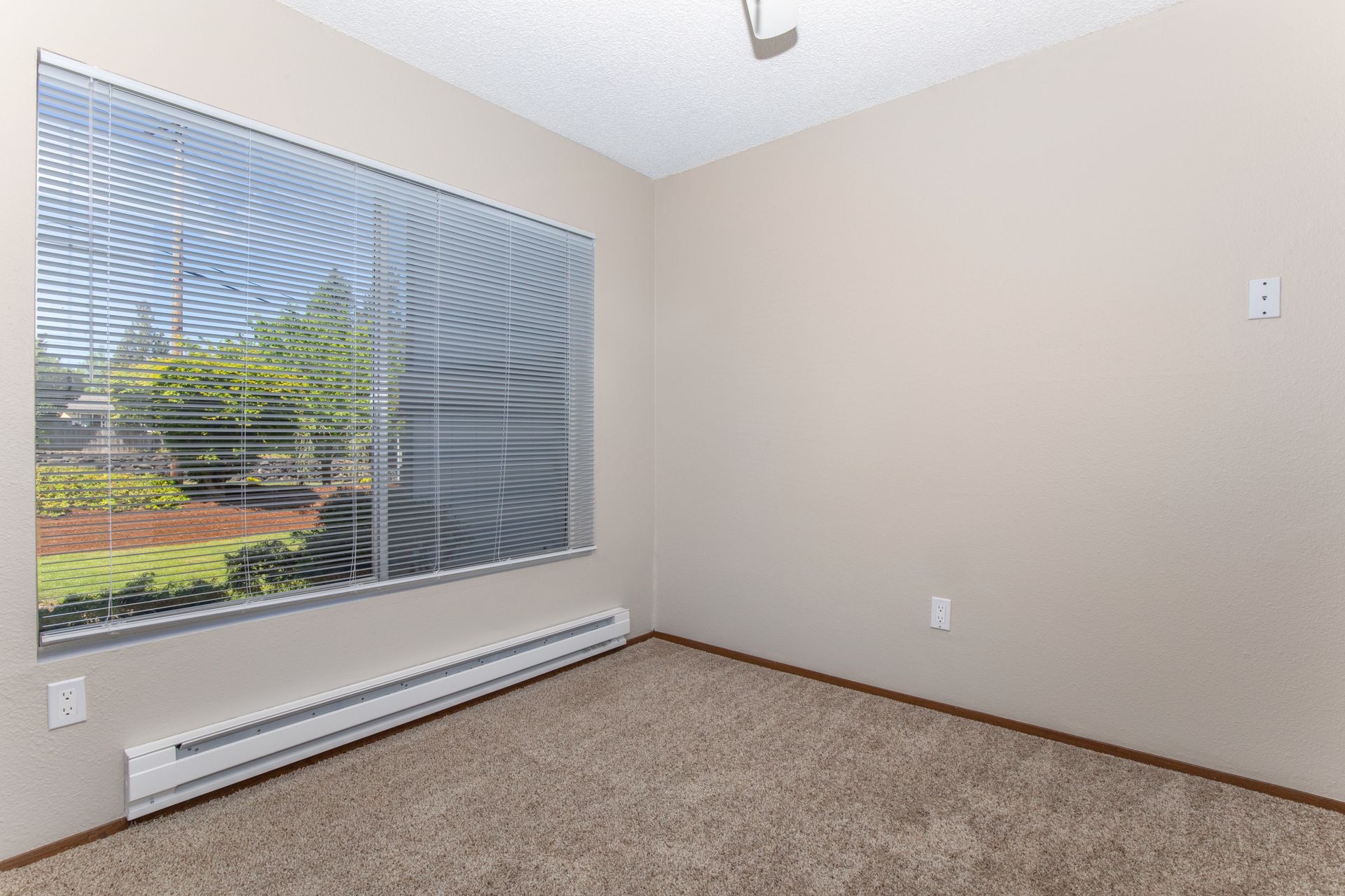 An empty room with a large window and blinds.