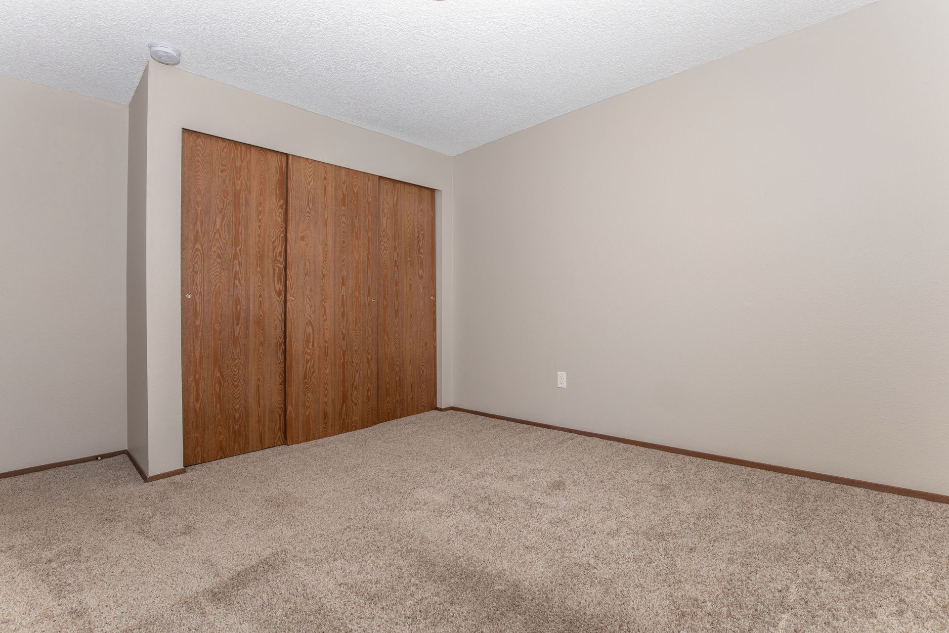 An empty bedroom with a closet and a carpeted floor.