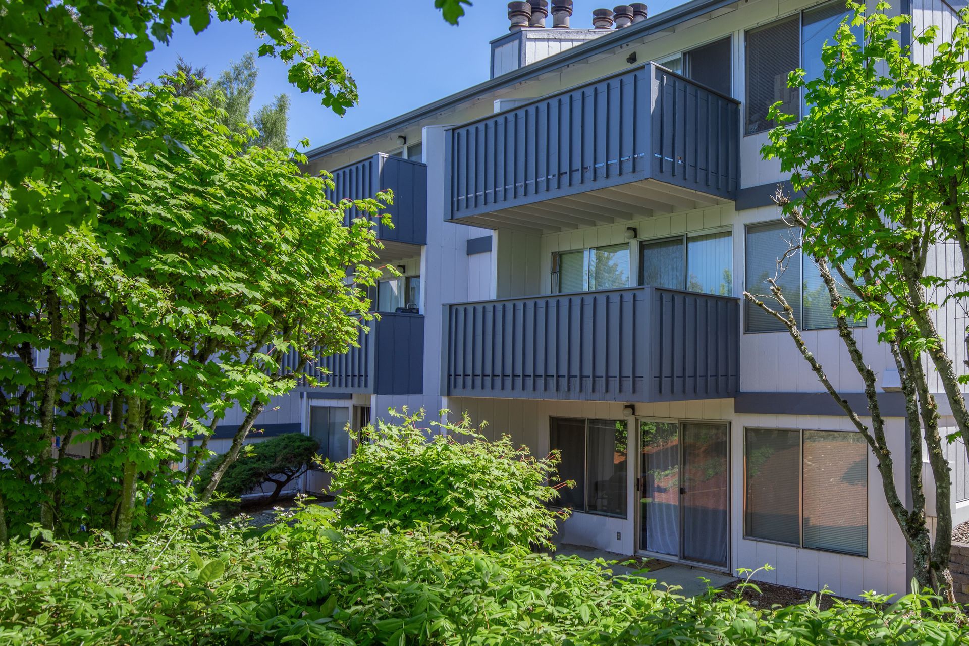 A large apartment building with balconies and trees in front of it.