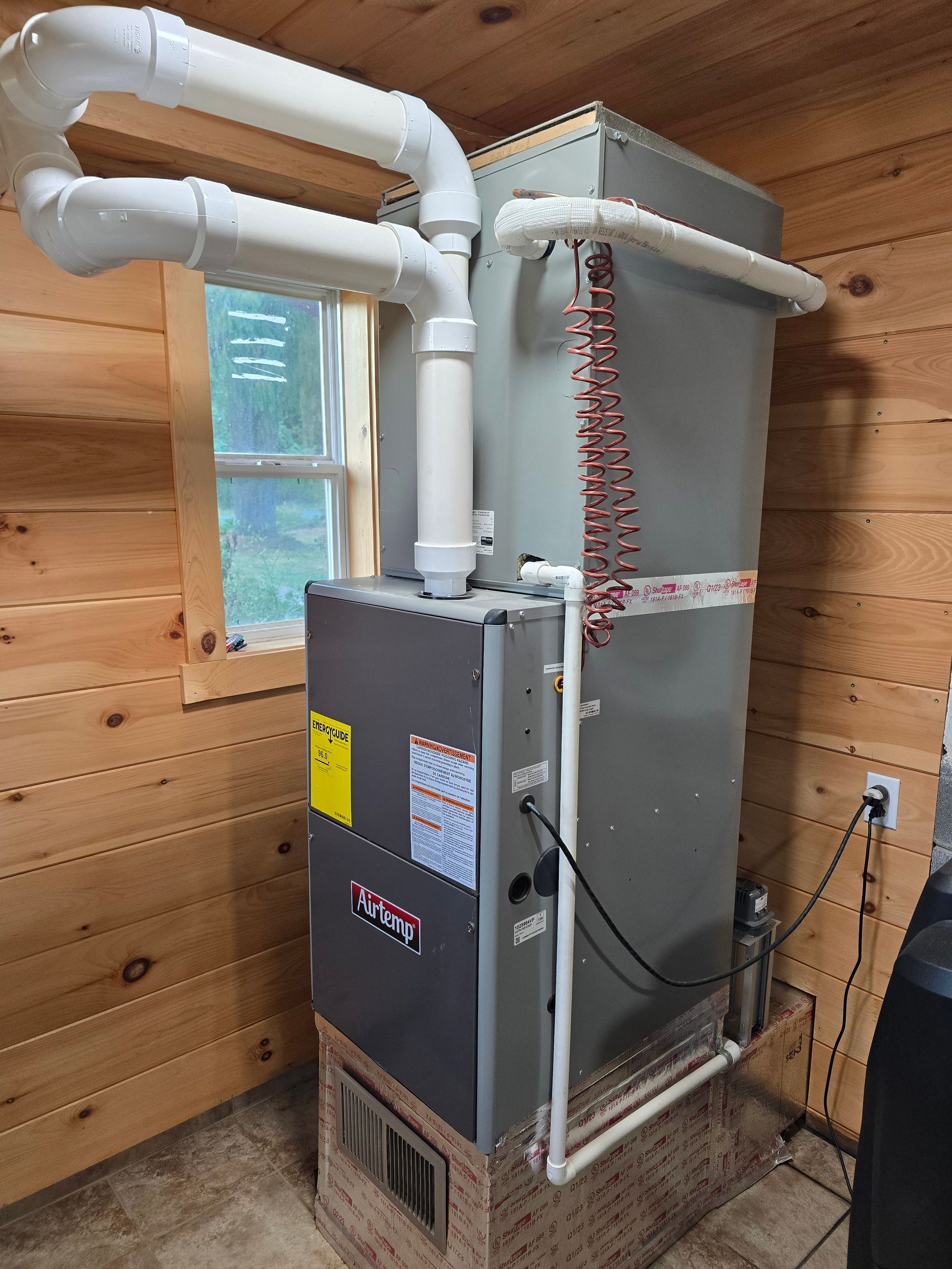 Technician repairs an outdoor AC unit; white and rust-colored, blue shirt, outdoors.