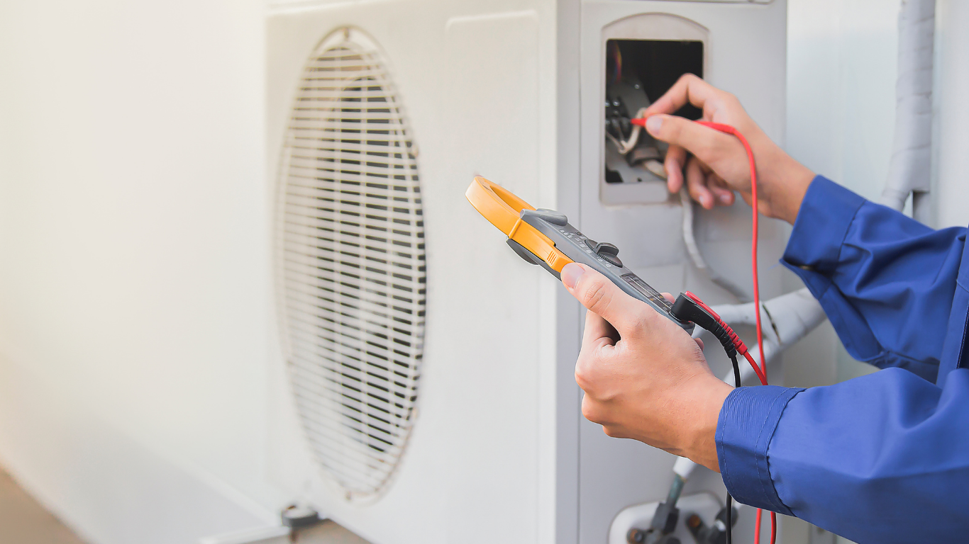 HVAC technician using a multimeter to inspect an outdoor air conditioning unit.