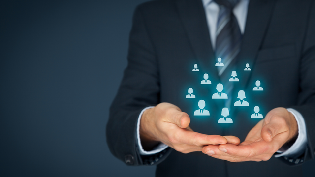 Man in suit holding glowing icons of people.