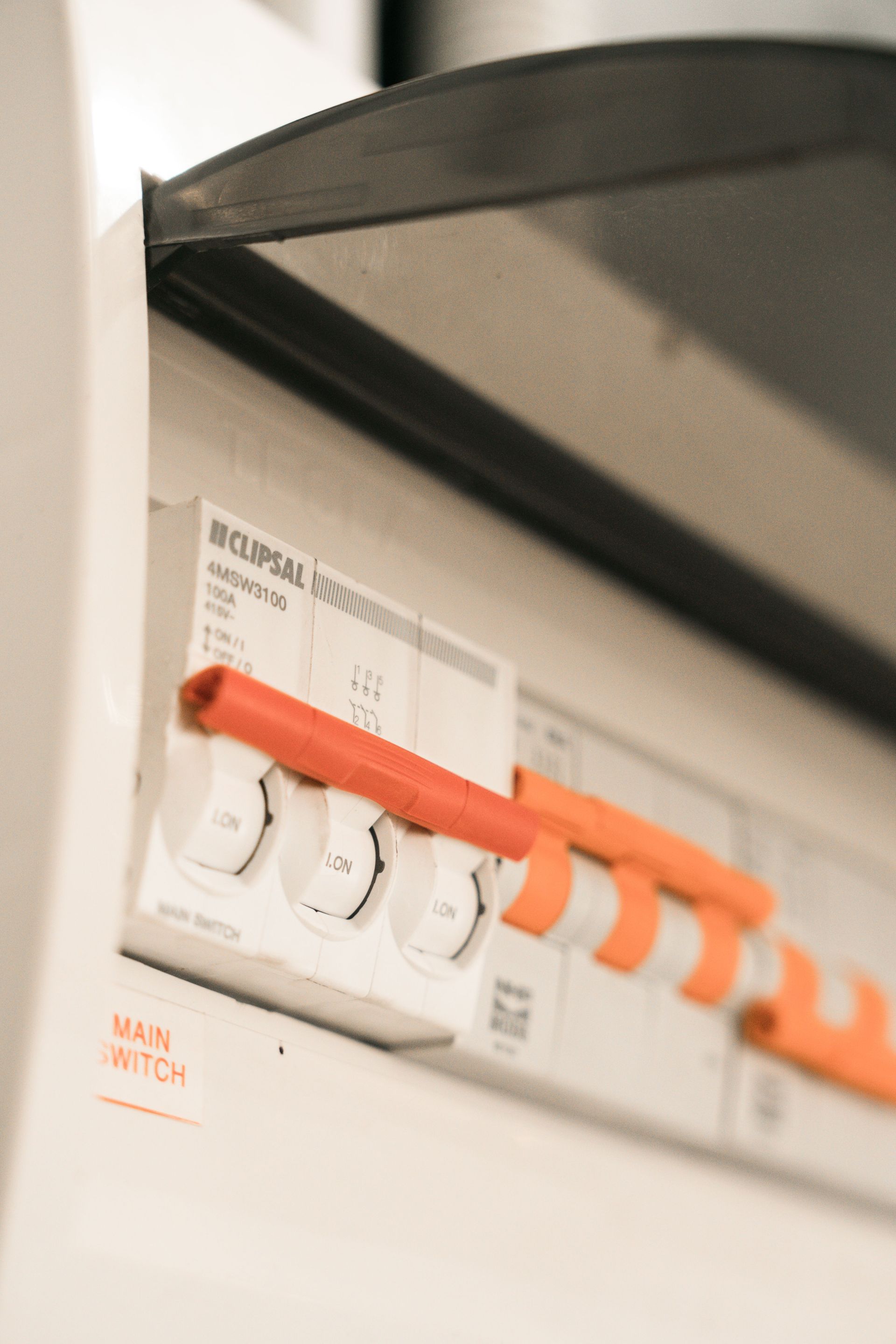 Close-up of an electrical breaker panel with orange switches under a black cover.