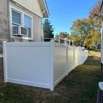 A white vinyl fence is sitting next to a house.