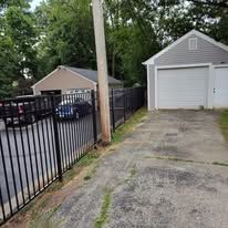 A garage with a fence around it and a car parked in front of it.