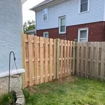 A wooden fence is in the backyard of a house.
