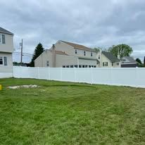 There is a white fence in the backyard of a house.