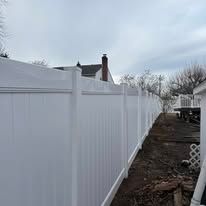 A white vinyl fence is sitting next to a house.