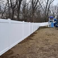 A white vinyl fence surrounds a playground in a backyard.