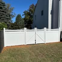 A white vinyl fence with a gate in front of a house.