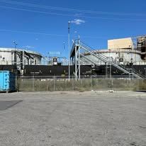 There is a blue dumpster in the middle of a parking lot.