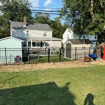 A backyard with a fence and a house in the background.