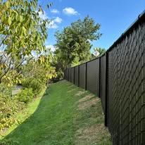 A black fence surrounds a lush green field.