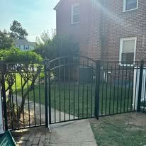 A black metal fence is in front of a brick house.