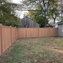 A wooden fence is in the backyard of a house.
