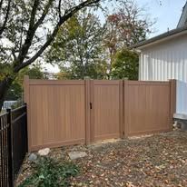A wooden fence with a gate in front of a house.