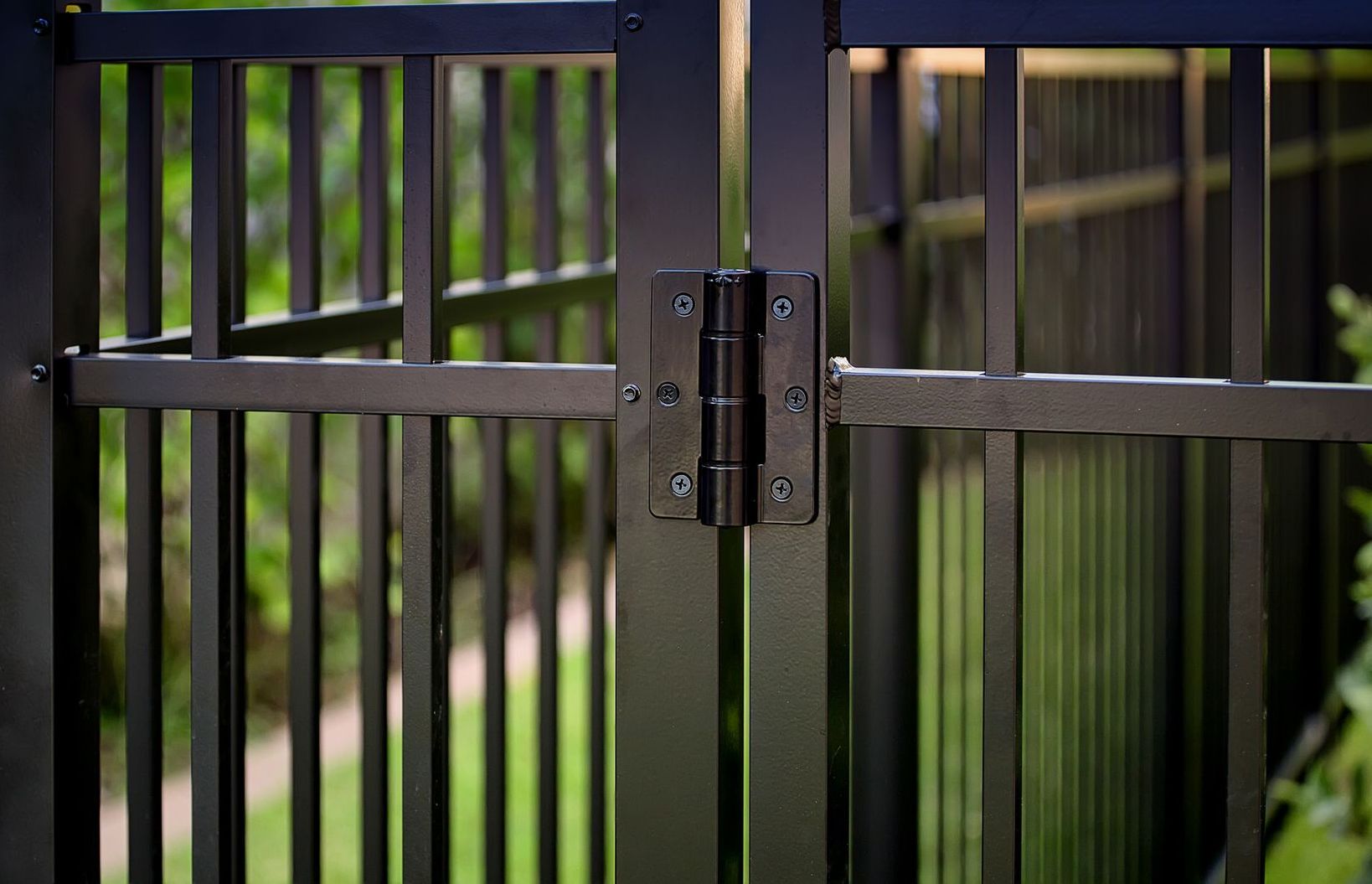 A close up of a black metal gate with a black hinge.