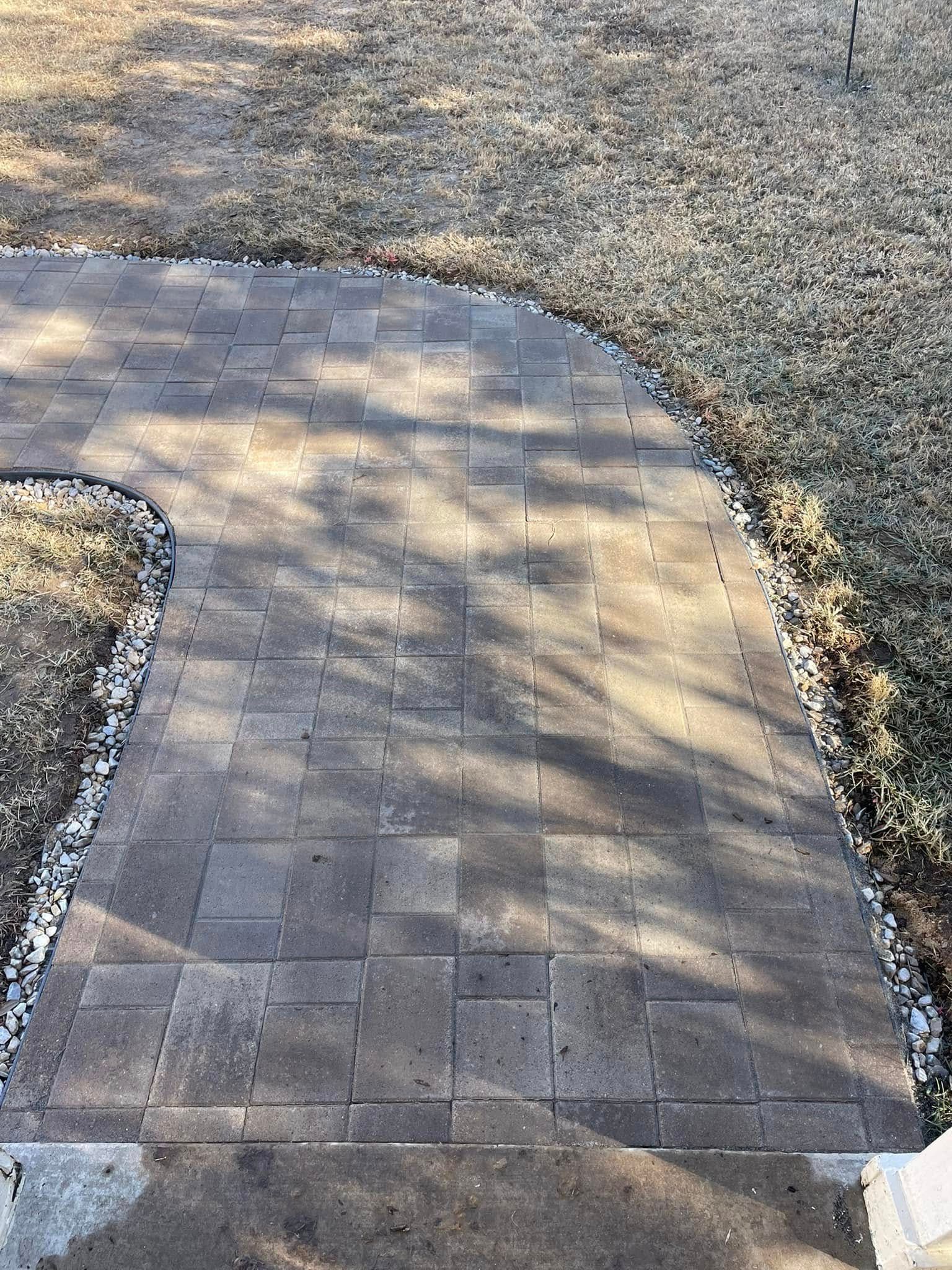 A brick walkway going through a lush green field.