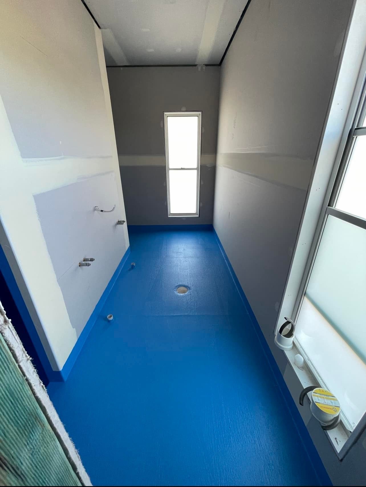 A Bathroom with a Blue Floor and a Window — Waterproofing Solutions in Toowoomba, QLD