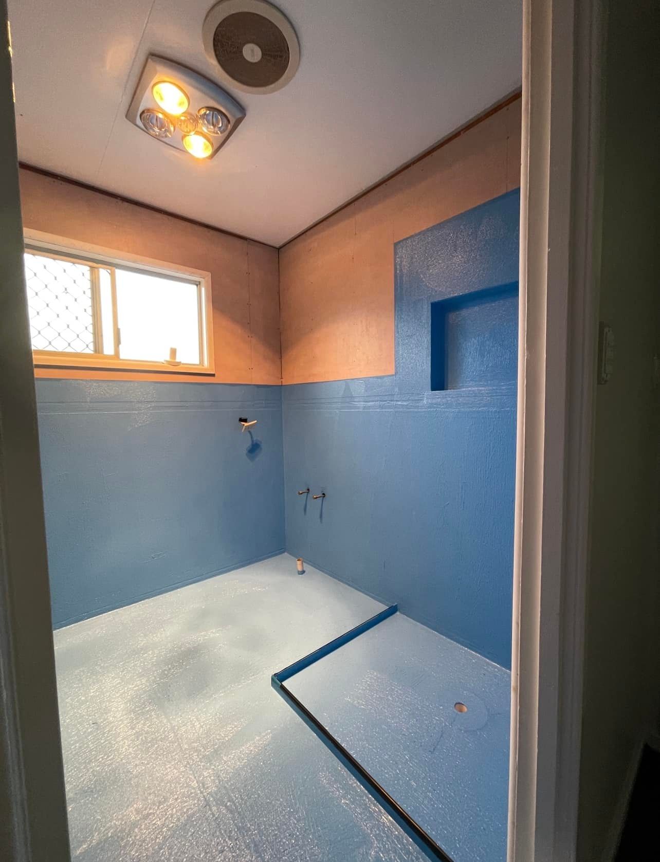A Bathroom with Blue Walls and a Fan on the Ceiling — Waterproofing Solutions in Toowoomba, QLD