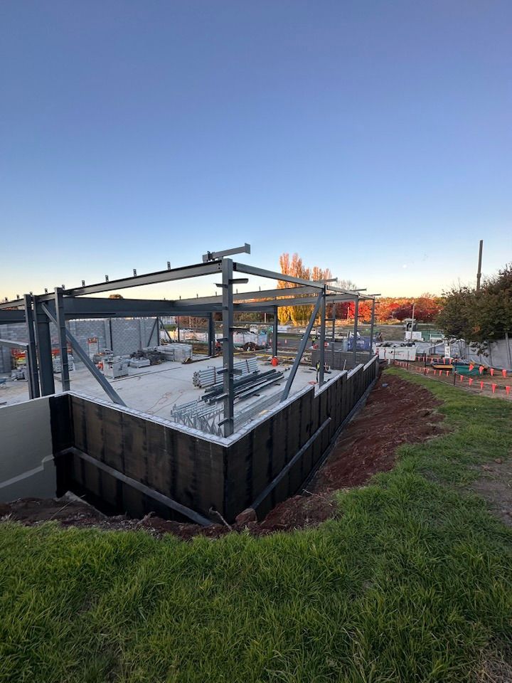 A Large Metal Structure is Being Built in a Grassy Field — Waterproofing Solutions in Toowoomba, QLD