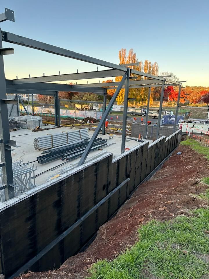 A Large Metal Structure is Being Built on Top of a Dirt Field — Waterproofing Solutions in Toowoomba, QLD