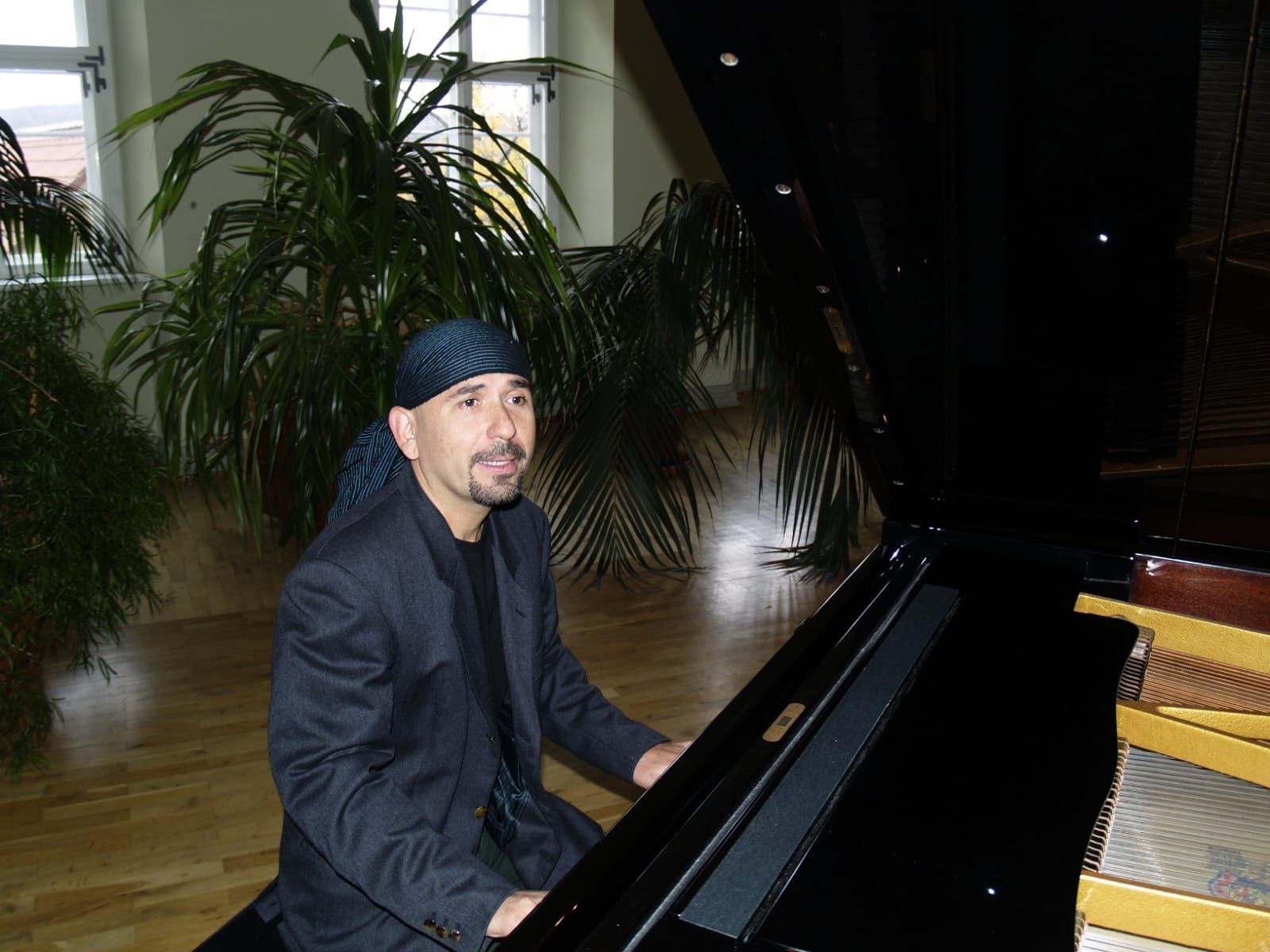 Ein Mann im schwarzen Anzug sitzt an einem Klavier