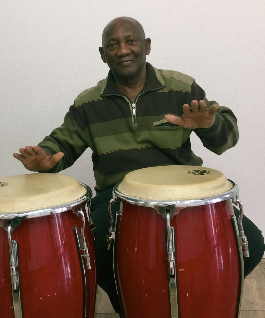 Ein Mann in einem grün-schwarz gestreiften Hemd spielt Schlagzeug