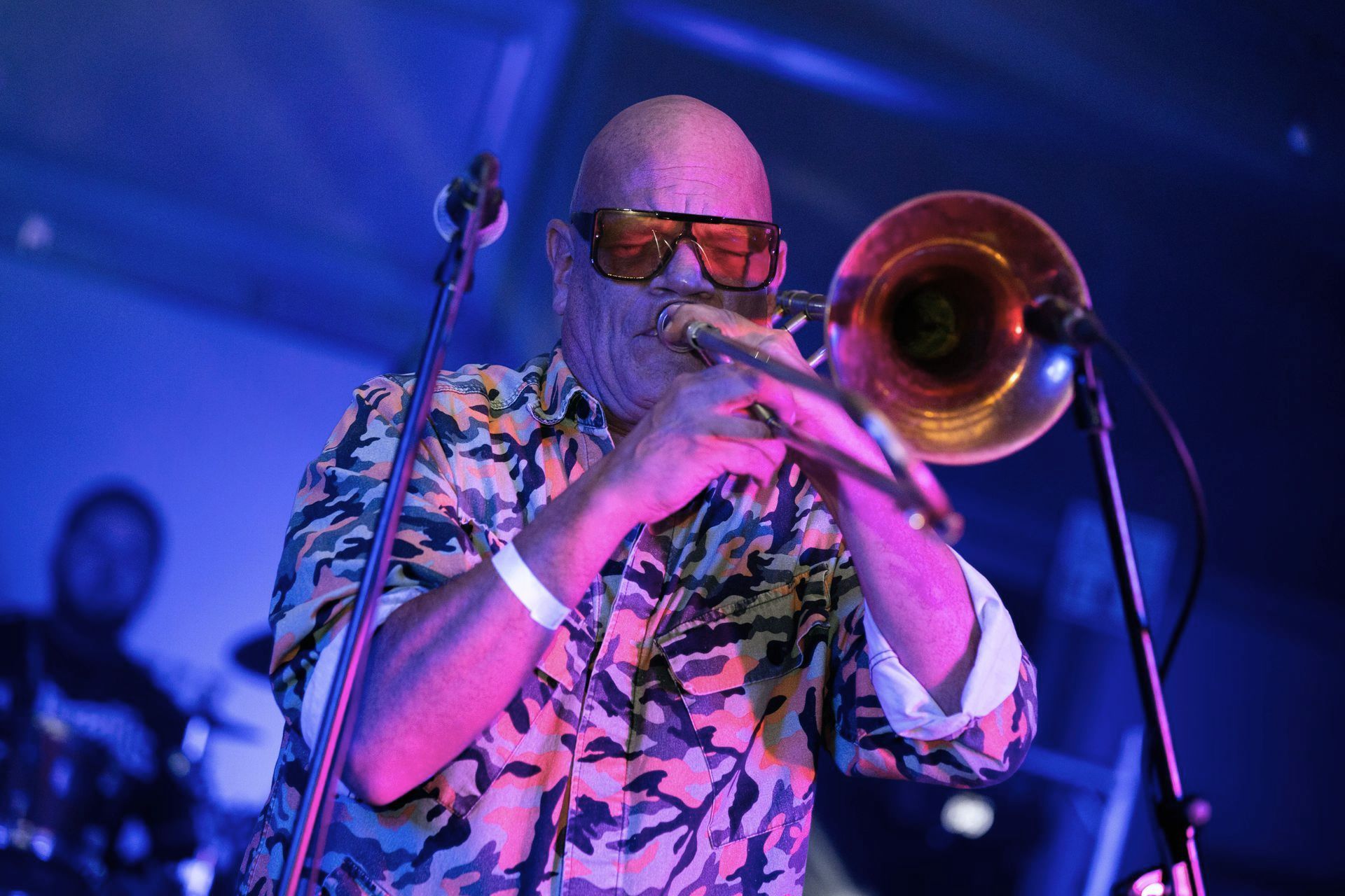 Ein Mann mit Sonnenbrille spielt auf einer Bühne Posaune.