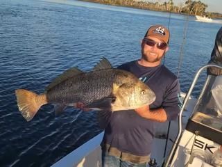 A man is holding a large fish on a boat in the water.