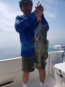 A man is holding a large fish on a boat.
