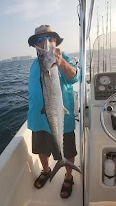 A man is holding a large fish on a boat.