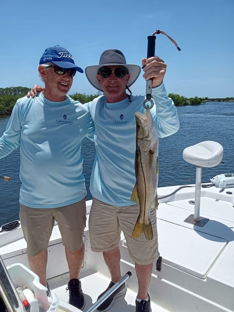 Two men are fishing in the ocean with a large fish in the water.